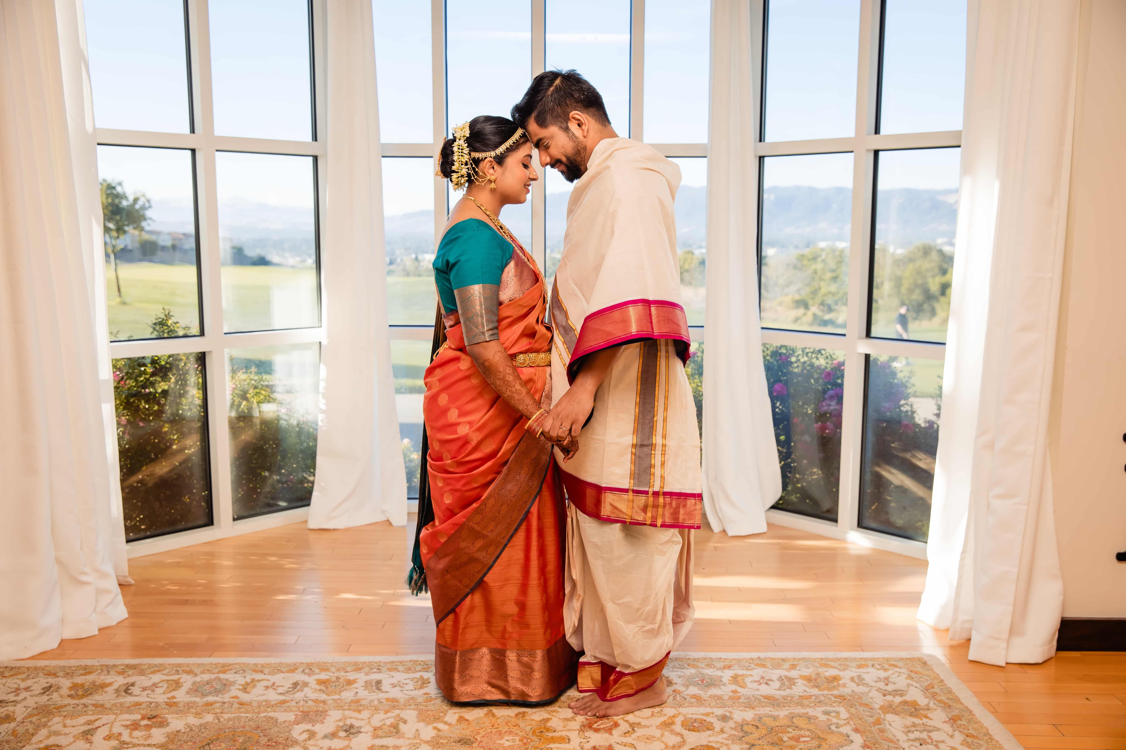 Indian couple in traditional wedding attire by windows